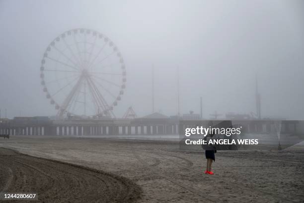 Person stands on the beach near Steel Pier on a foggy morning in Atlantic City, New Jersey on October 26, 2022. - Ten years after the devastating...