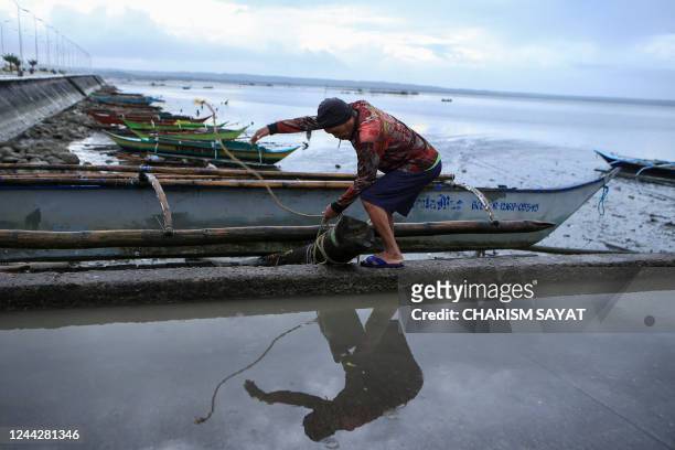 Fisherman secures his boat at the bay in Sorsogon, in the Philippines' Sorsogon province on October 28 ahead of the expected landfall of Tropical...
