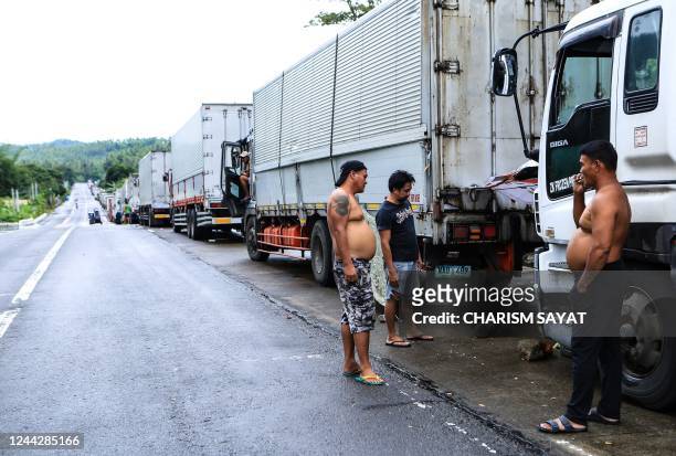 Drivers stand next to dozens of cargo trucks lined up along a highway near Matnog pier, in Sorsogon province, south of manila on October 28 after...