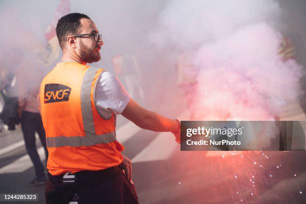 Striking railway workers from the SNCF centre in Versailles hold up red flares during a demonstration in which several hundred people took part,...