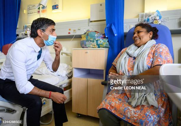 Britain's Prime Minister Rishi Sunak, wearing a face covering, speaks with patient Sreeja Gopalan during his visit to Croydon University Hospital in...