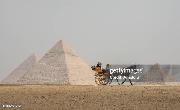 People go on a carriage in front of Great Pyramid of Giza, the Pyramid of Khafre, and the Pyramid of Menkaure in Cairo, Egypt on October 27, 2022.