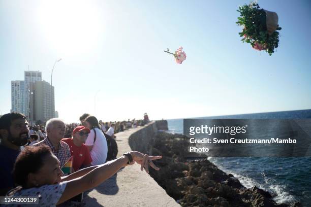 Cubans throw flowers into the ocean at Havana's Malecon waterfront to honor the 63rd anniversary of the disappearance of revolution commander Camilo...