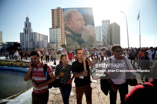 Cuban carries an image of late revolution leader Fidel Castro as arriving at Havana's Malecon waterfront to honor the 63rd anniversary of the...