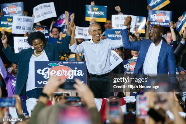 Former President Barack Obama raises hands with Democratic Gubernatorial candidate Stacey Abrams and Sen. Raphael Warnock at a campaign event for...