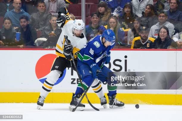 Marcus Pettersson of the Pittsburgh Penguins and Andrei Kuzmenko of the Vancouver Canucks battle for the puck during the first period of their NHL...
