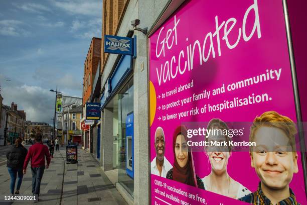 Members of the public pass Get Vaccinated public health guidance display boards on 28 October 2022 in Slough, United Kingdom. The boards were...