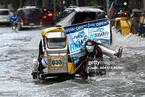 Tricycle carries passengers along a flooded street in Manila on October 29 following heavy rain brought by Tropical Storm Nalgae. - Severe Tropical...