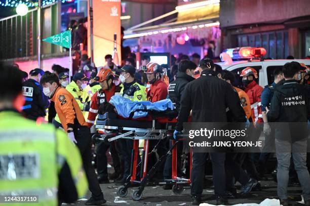 Person, believed to have suffered from cardiac arrest, is transported on a stretcher in the popular nightlife district of Itaewon in Seoul on October...