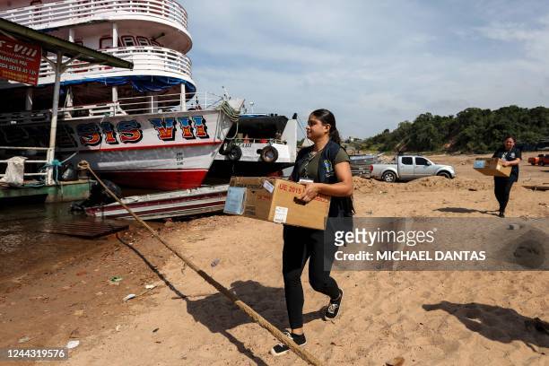 Members of the Electoral Justice carry electronic voting machines to a boat for their distribution to indigenous communities along the Rio Negro...