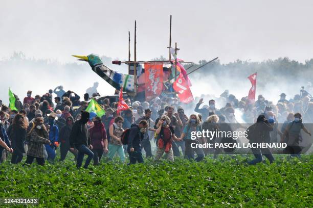 Activists walk among tear gas following clashes with riot mobile gendarmes during a demonstration called by the collective "Bassines Non Merci"...