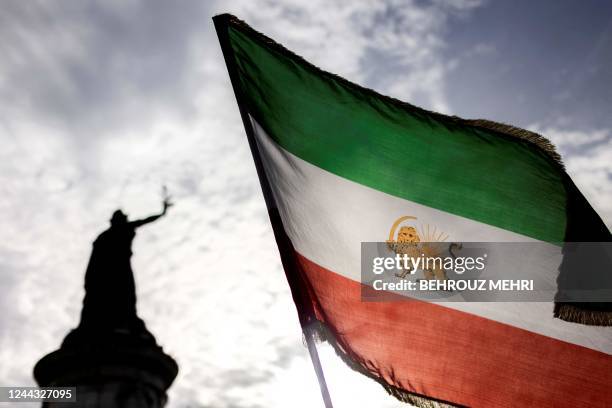 An Iran's pre-Islamic revolution flag flies near the statue of Marianne during a rally in support of the demonstrators in Iran, at the Place de la...