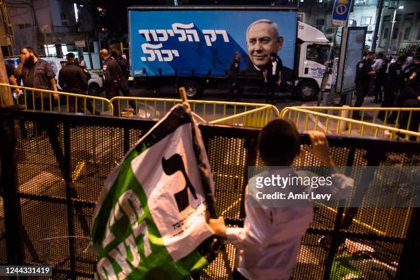 Ultra Orthodox boy holds a 'Yahadut Htora' party flag as he islooking at the 'Likud party' campaign modified truck with a poster showing former...