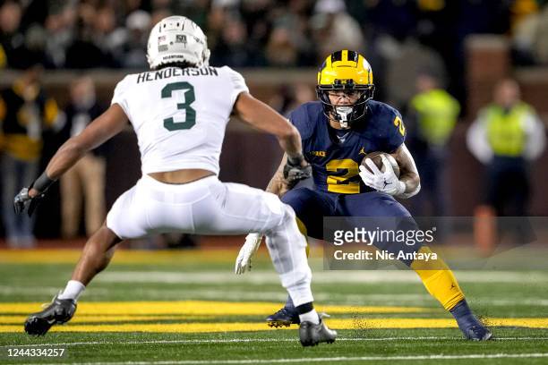 Blake Corum of the Michigan Wolverines runs the ball against Xavier Henderson of the Michigan State Spartans during the first quarter at Michigan...