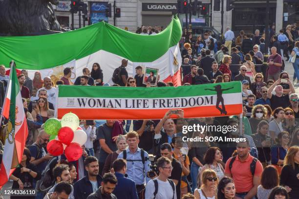 Protesters hold a "Woman, life, freedom" banner with the colours of the Iranian flag during the demonstration. Iranians and other protesters continue...