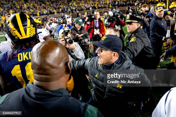 Head coach Jim Harbaugh of the Michigan Wolverines calms down Eyabi Okie of the Michigan Wolverines after defeating the Michigan State Spartans at...