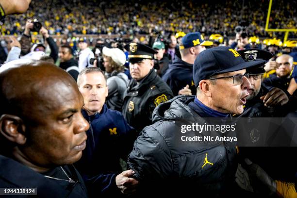 Head coach Jim Harbaugh of the Michigan Wolverines calms down his team after defeating the Michigan State Spartans and waiting to shake hands with...