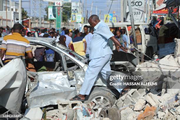 Residents walk among debris from a destroyed buildings in Mogadishu on October 30, 2022 after an car bombing targeted the education ministry on...