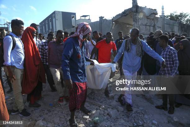 Residents carry the body of a victim in Mogadishu on October 30, 2022 after an car bombing targeted the education ministry on October 29, 2022. - Two...