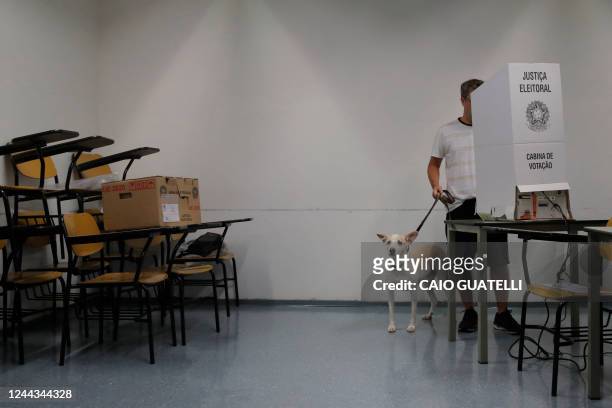 Man votes holding his dog's leash at a polling station in Sao Paulo, Brazil, on October 30, 2022 during the presidential run-off election. After a...