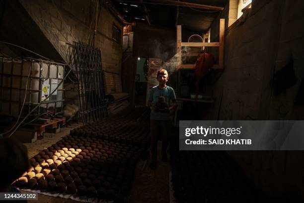 Nader Qishta, a 12-year-old Palestinian from Rafah, shapes olive pomace into briquettes at his home in the southern Gaza Strip on October 30, 2022. -...