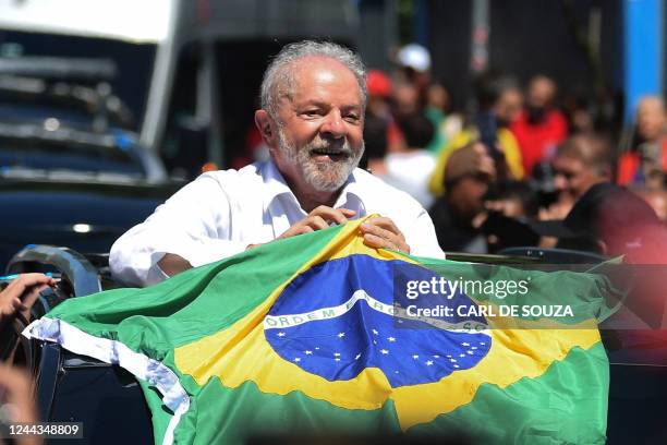 Brazilian former President and candidate for the leftist Workers Party Luiz Inacio Lula da Silva holds a Brazilian flag while leaving a polling...