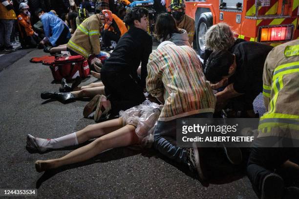 This picture taken on October 29, 2022 shows emergency workers and others assisting people who were caught in a Halloween stampede in the district of...