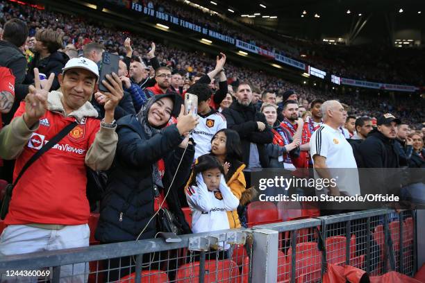 Family of Manchester United fans look on, filming with a mobile phone as a young girl covers her ears during the Premier League match between...