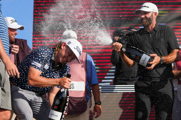 Team Captain Dustin Johnson of 4 Aces GC sprays champagne on Team Captain Cameron Smith of Punch GC on the podium after the team championship...