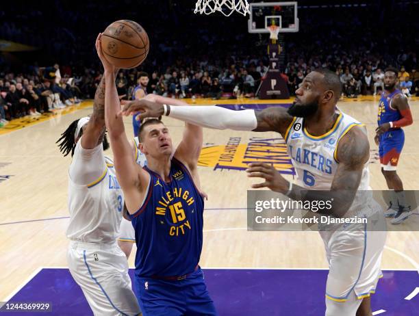 Anthony Davis of the Los Angeles Lakers knock the ball out of the hands of Nikola Jokic of the Denver Nuggets with LeBron James of the Los Angeles...