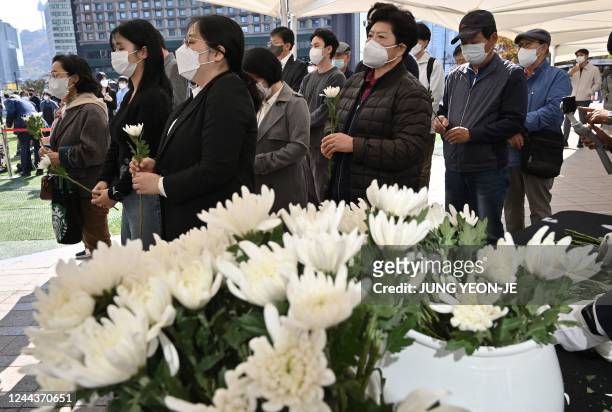 Mourners holding flowers wait in line to pay tribute in front of a joint memorial altar for victims of the deadly Halloween crowd surge, outside the...