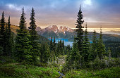 Glacial mountain Garibaldi lake with turquoise water in the middle of coniferous forest at sunset.