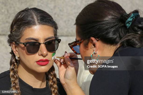 Woman paints the flag of Iran on another woman's face during the demonstration calling for justice for Mahsa Amini who died in a hospital in Tehran,...