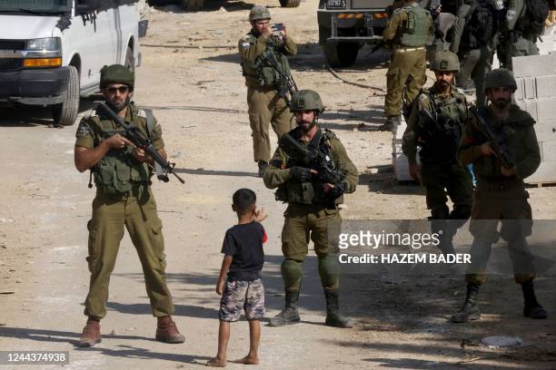 Palestinian child gestures at Israeli forces standing guard as army bulldozers demolish a building in the Palestinian city of Hebron, in the occupied...