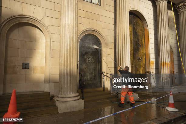Worker cleans orange paint from the facade of the Bank of England after activists from the "Just Stop Oil" environmental coalition targeted the...