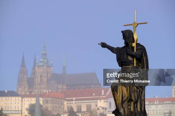 The statue of John Nepomucene and the Prague Castle are seen from the medieval stone arch bridge called 'Charles Bridge' on October 9, 2022 in...