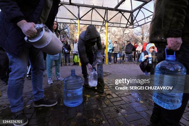 Local residents wait in line to collect water from a public water pump in a park of Kyiv on October 31, 2022. - Ukraine suffered sweeping blackouts...