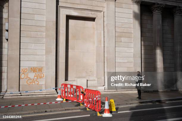 Members of the public pass-by the sprayed yellow paint on the walls of the Bank of England left by members of the climate change activists group...