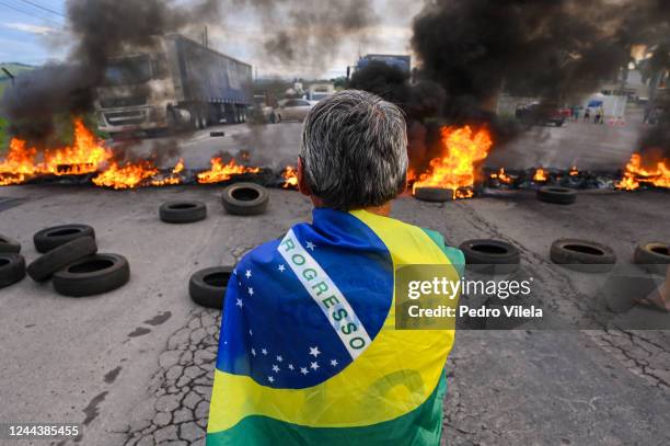 Demonstrator wearing a Brazilian flag stands as truck drivers and supporters of President Jair Bolsonaro block 491 road with a burning barricade to...