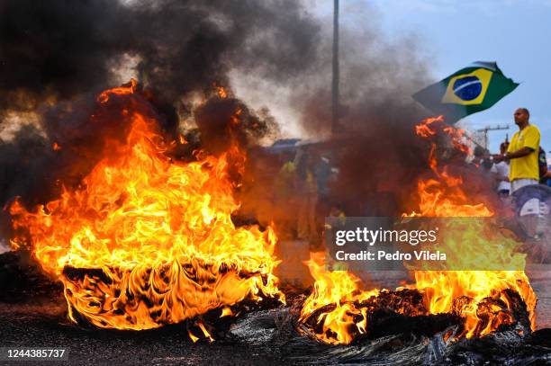 Demonstrator waves a Brazilian flag as truck drivers and supporters of President Jair Bolsonaro block 491 road with a burning barricade to protest...