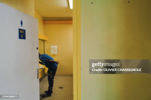 Young migrant brushes his teeth in a bathroom at the Marcel Dargent gymnasium where he is billeted in Lyon, eastern France on October 27, 2022.