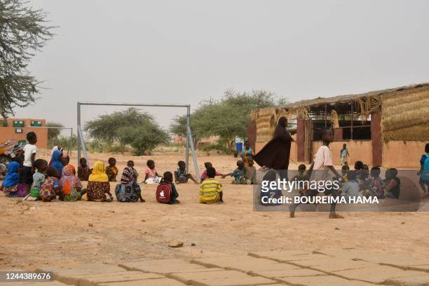 Teacher and her pupils play in a yard at a school created near a site for displaced people on the outskirts of Ouallam, Niger, on October 26, 2022. -...