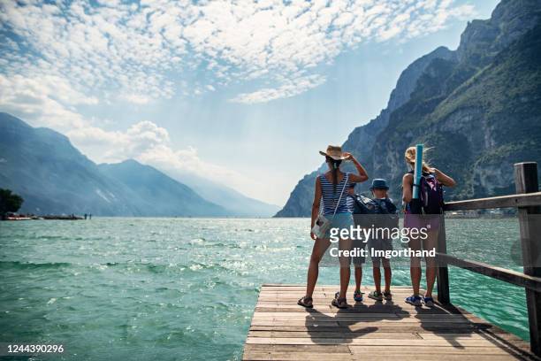 famiglia in piedi sul molo e vista sul lago di garda - vacanze foto e immagini stock