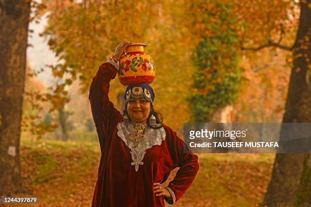 Tourist wearing traditional Kashmiri dress poses amid maple trees at Nishat Garden in Srinagar on November 1, 2022.