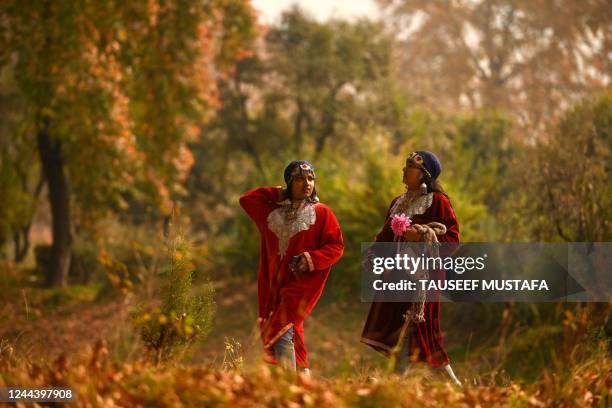 Tourists wearing traditional Kashmiri dress walk amid maple trees at Nishat Garden in Srinagar on November 1, 2022.