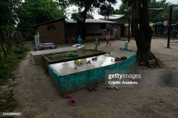 Salvadoran woman walks in front of the graves of her relatives buried in the backyard of their house, within the framework of the Day of the Dead, in...