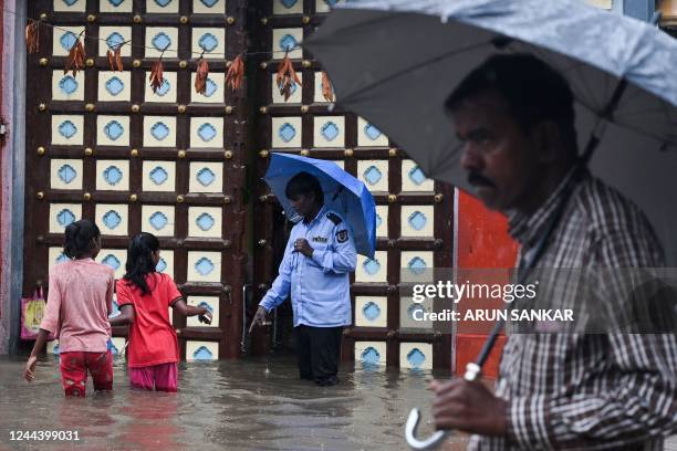 People make their way through a flooded street during a heavy monsoon rainfall in Chennai on November 1, 2022.