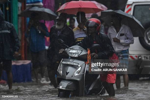 People make their way through a flooded street during a heavy monsoon rainfall in Chennai on November 1, 2022.