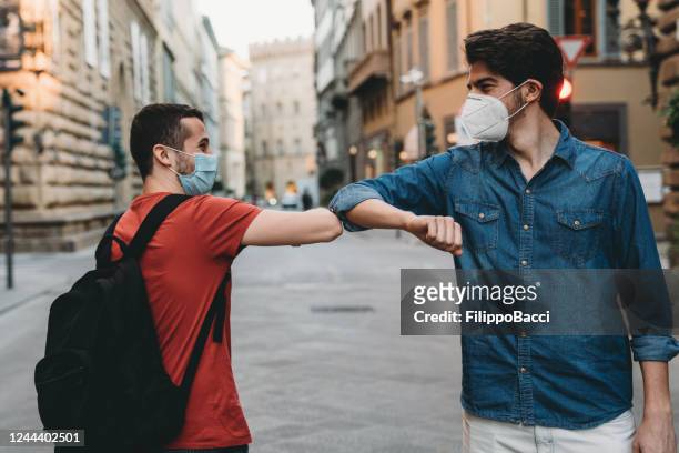 two friends greeting each other with the elbow - elbow bump stock pictures, royalty-free photos & images