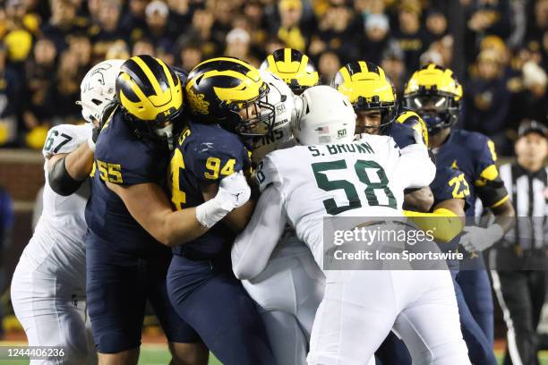Michigan defensive players and Michigan State offensive players get tangled up together during a play during a college football game between the...